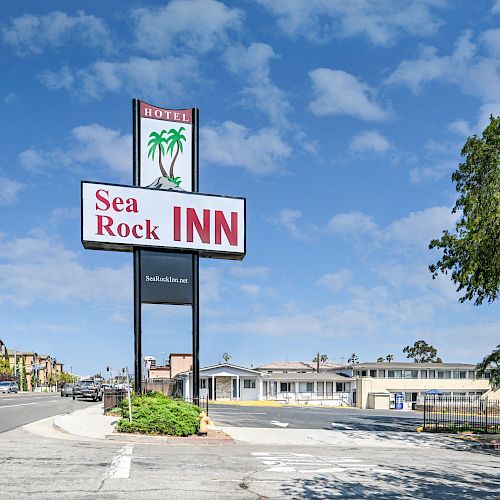 A street view showing a sign for Sea Rock Inn with buildings and a clear sky in the background.