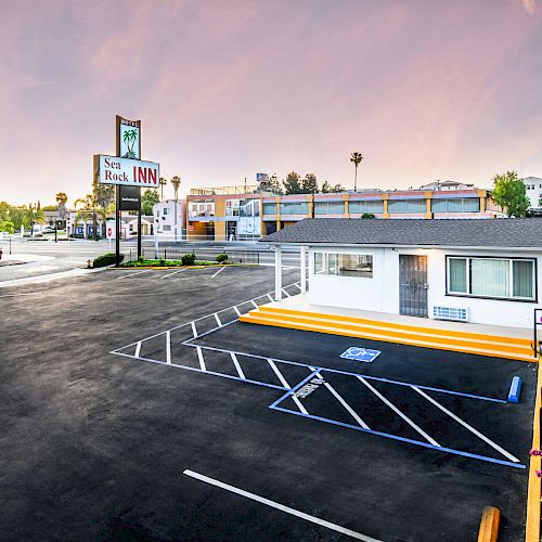 The image shows a quiet motel with an empty parking lot and a sign that reads 