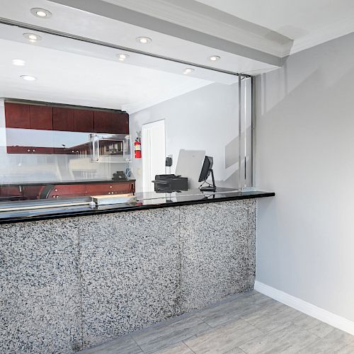 An image of a modern reception area with a granite counter, computer terminal, and cabinets behind the counter in a clean, bright setting.