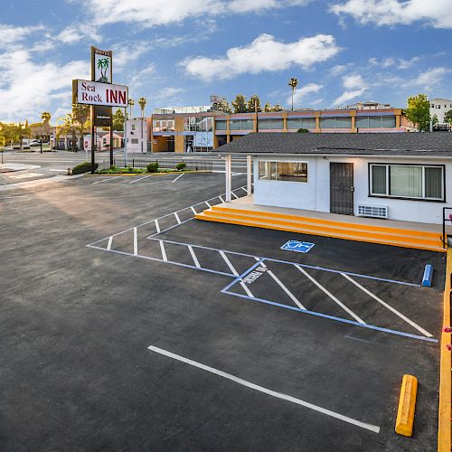 An image of a motel with a parking lot, showing clear parking spaces including a disabled spot, and the motel sign reading 