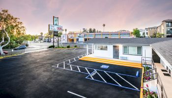 The image shows a motel parking lot with a sign reading 