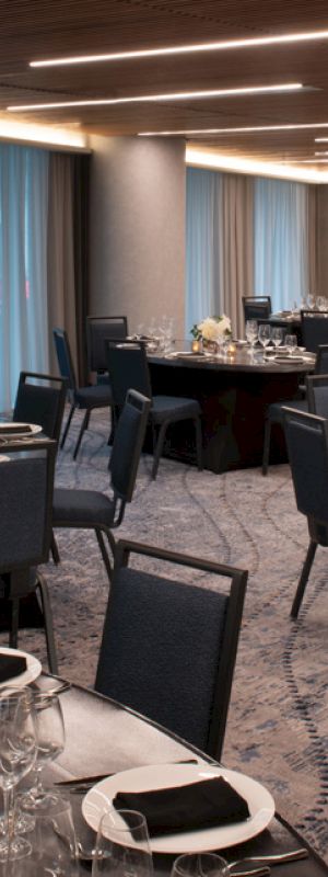 The image shows an elegant dining room set up for an event, with several round tables covered in black tablecloths, decorated with flowers, and set with dinnerware ending the sentence.