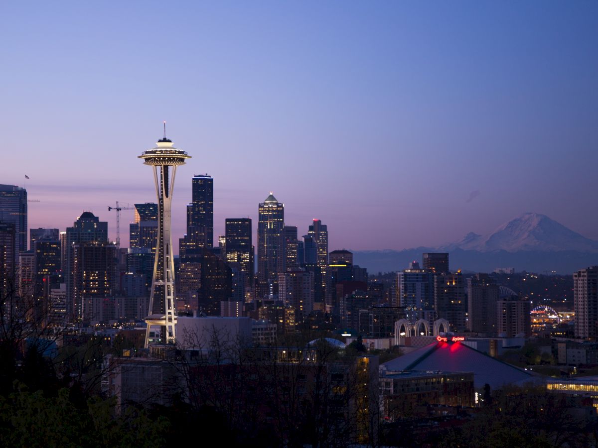 A twilight view of the Seattle skyline featuring the Space Needle with Mt. Rainier in the background.