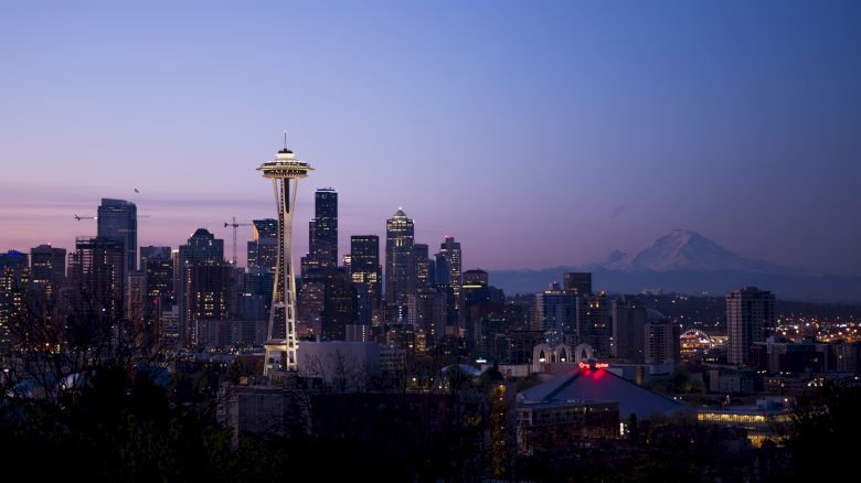 A twilight view of the Seattle skyline featuring the Space Needle with Mt. Rainier in the background.