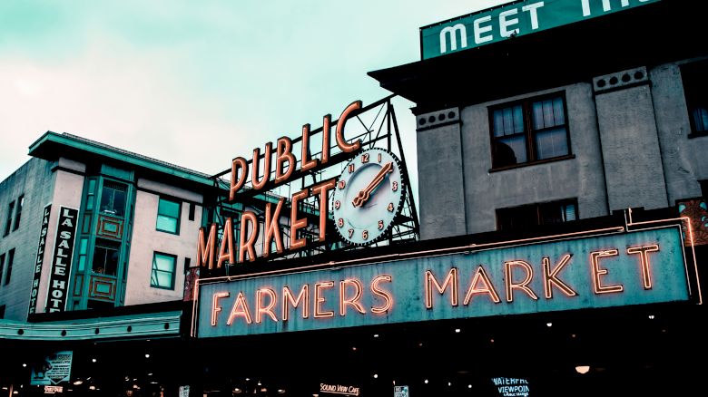 The image shows the iconic signage for a public market and farmers market, with a clock, located on buildings in an urban setting.